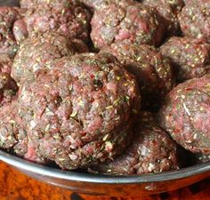 a metal bowl filled with meatballs on top of a wooden table