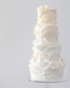 a three tiered white wedding cake with ruffles