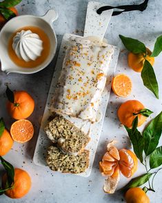 an orange cake with icing and sprinkles next to some tangerines