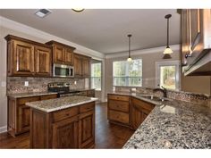 a large kitchen with granite counter tops and wooden cabinets, along with hardwood flooring