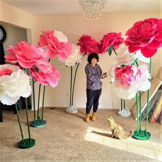 a woman standing in front of large paper flowers