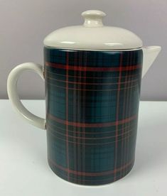 a tea pot with a lid and plaid pattern on the outside, sitting on a white surface