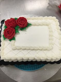 a cake with white frosting and red roses on it