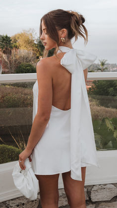 a woman in a white dress looking out the window with her back to the camera