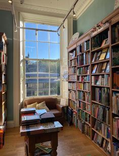 a living room filled with lots of books on top of a hard wood floor next to a window