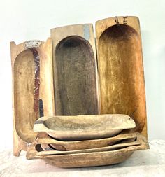 three wooden bowls are stacked on top of each other in front of a white wall