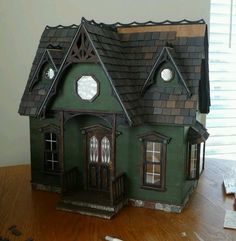 a green doll house sitting on top of a wooden table