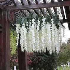 white flowers hanging from the side of a wooden structure