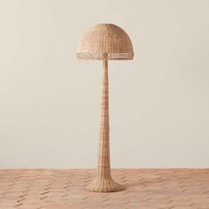 a wicker lamp on a wooden table with a white wall in the back ground