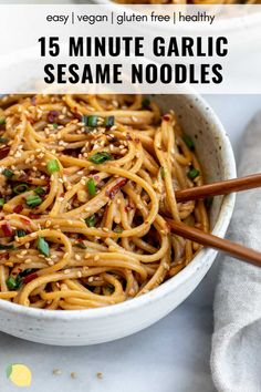 a white bowl filled with sesame noodles and topped with chopsticks on the side