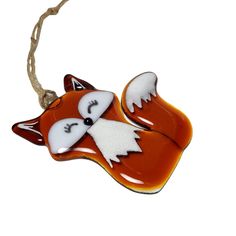 a glass ornament with a fox on it's head and tail hanging from a rope