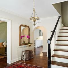 an entry way with stairs, mirror and stool