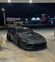 a black sports car parked in front of a gas station at night with no one around