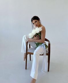 a woman sitting in a chair holding a bouquet of flowers