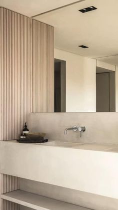 a bathroom sink sitting under a mirror next to a wooden wall mounted faucet