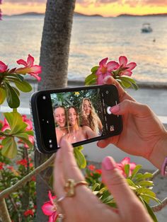 a woman taking a selfie with her cell phone in front of some pink flowers