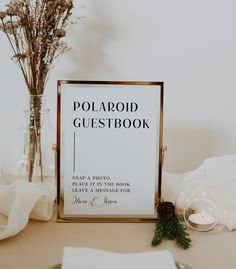 a polaroid guest book sitting on top of a table next to a vase filled with flowers