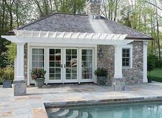 a pool house with a stone patio and swimming pool