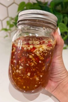 Impress your taste buds with Vietnamese Fish Sauce showcased in a glass mason jar which includes fresh garlic and Thai chili peppers.