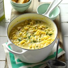 a large pot filled with pasta and broccoli on top of a wooden table