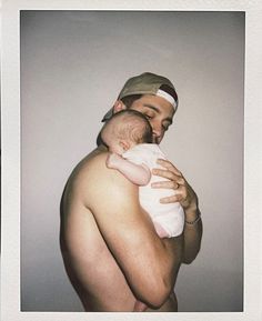 a man holding a baby in his arms and wearing a hat on top of his head