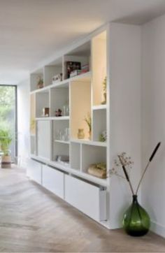 a living room filled with lots of white shelves and furniture next to a large window