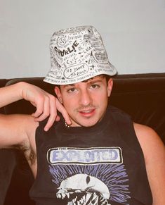 a young man wearing a black shirt and a white hat is sitting on a couch