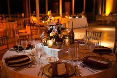 the table is set for dinner with white linens and gold place settings, along with wine glasses