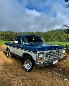 an old pickup truck parked on a dirt road