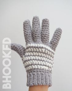 a hand wearing a gray and white crocheted mitt