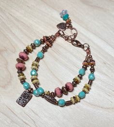 Beautiful double strand boho bracelet, one of my favs! This was created using Czech Picasso glass beads in opaque dusty rose, light aqua blue, cream, and dark beige.  I have also used  antique copper accent beads throughout, and an antique copper charm etched with a lotus flower.  The extender chain is finished with a small copper heart charm, and a Czech bell flower bead dangle.  This beautiful bracelet is perfect for everyday, and makes a wonderful gift! Bracelet best fits a wrist size between 6-3/4" - 7-1/2".  If a longer extender is needed, please leave a note at checkout. Matching earrings: https://www.etsy.com/listing/1659804395/antique-copper-lotus-flower-earrings?click_key=3c3d06fb1210a703d14f4e975a7a44914a5b9731%3A1659804395&click_sum=ac821664&ref=shop_home_active_1&frs=1&sts=1 Th Copper Heart, Jewelry Styles, Gift Bracelet, Hippie Bracelets, Bohemian Handmade, Multi Strand Bracelet, Light Aqua, Boho Bracelet, Glass Bracelet