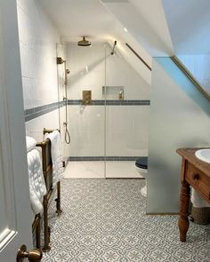 a bathroom with blue and white tile flooring next to a wooden sink vanity under a slanted ceiling