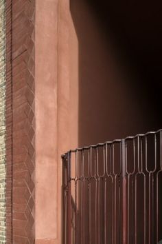 a red fire hydrant sitting next to a tall brick building with a metal fence