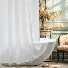 a bath tub sitting next to a white curtain in a bathroom with a chair and table