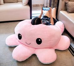 a person laying on the floor with a pink octopus pillow in front of their face