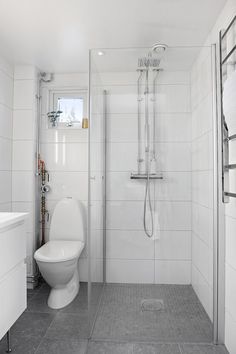 a white toilet sitting next to a shower in a bathroom on top of a tiled floor