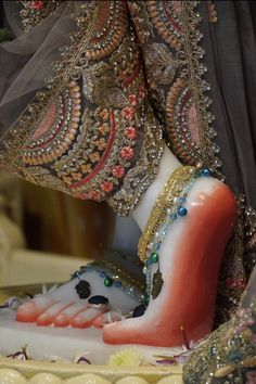 a woman's feet with beads and jewelry on top of a cake in the shape of a shoe