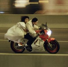 a man and woman riding on the back of a motorcycle