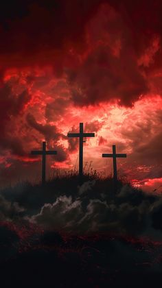 three crosses on top of a hill with red clouds in the sky behind them at sunset