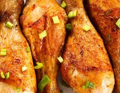 chicken legs with green onions and seasoning on a white plate, ready to be cooked