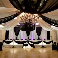 a room with black and white drapes, chandelier and couches on the floor