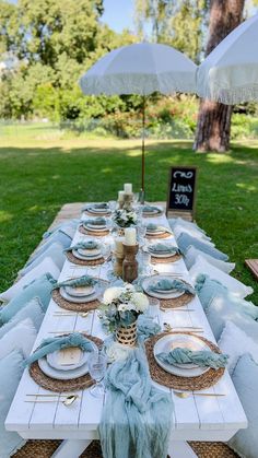 an outdoor table set up with plates and napkins