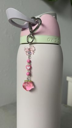 a pink and white water bottle with a key chain hanging from it's side