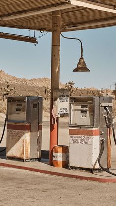 two old gas pumps sitting in an empty lot