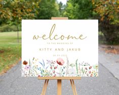 a welcome sign on an easel in front of some trees