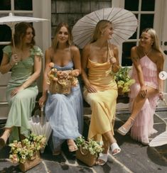 four women sitting on the steps with umbrellas over their heads and flowers in front of them