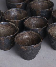 a bunch of small black bowls sitting on top of a table