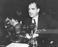 an old photo of a man sitting at a desk with microphones