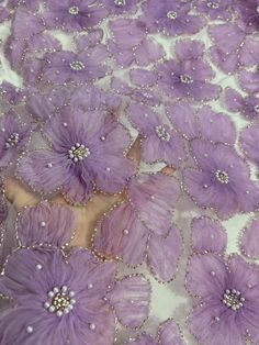 purple flowers on white fabric with pearls and beadings in the center, close up