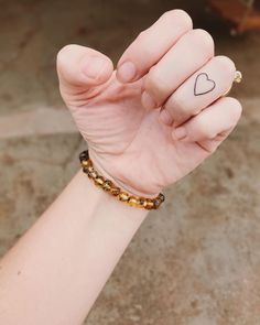 a person with a small heart tattoo on their wrist holding the hand of another person